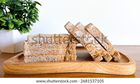 Sliced, stale bread with a moldy coating on a wooden plate. Concept: the dangers of food waste, improper shelf life, and sanitary risks.
