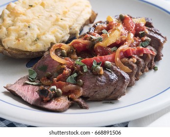 Sliced Steak Covered In A Sauce Of Tomatoes, Peppers, Onions And Seasoning, Accompanied With Twice Baked Potato