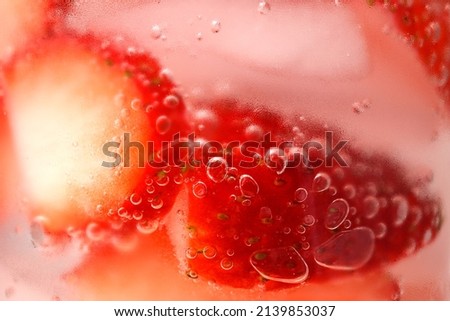 Sliced strawberries, ice cubes, cold water, water bubbles, condensation on glass