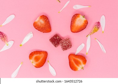 Sliced Strawberries On Pink Backdrop With Square Gummies And Flower Peddles.