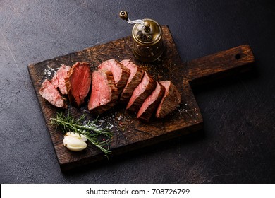 Sliced tenderloin Steak Roast beef on wooden cutting board on dark background - Shutterstock ID 708726799