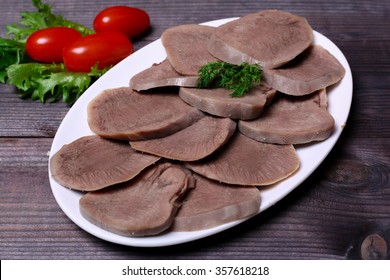 Sliced tongue on plate with parsley , tomato.