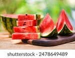 Sliced watermelon on a plate. Slices of juicy watermelon on the black plate on the concrete background with summer sun shadows