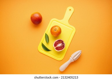 Sliced And Whole Blood Oranges And A Wooden Juicer On An Orange Background. Top View.