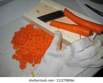 Sliced And Whole Peeled Carrots Prepared Using A Mandolin And Protective Glove On Kitchen Counter