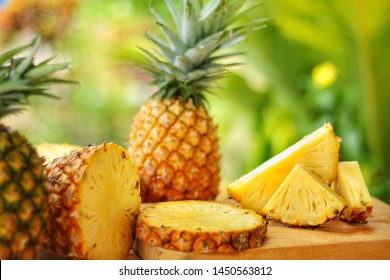 Sliced and whole of Pineapple(Ananas comosus) on wooden table with blurred 
 garden background.Sweet,sour and juicy taste.Have a lot of fiber,vitamins C and minerals.Food,Fruits or healthcare concept.