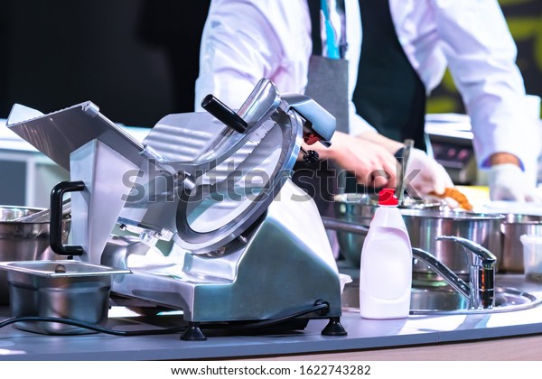 Slicer in the restaurant kitchen. Concept -
Slicer washed with detergent. Detergent for kitchen appliances.
Professional semi-automatic slicer. Machine with a cutting disc.
Grocery Store Equipment.