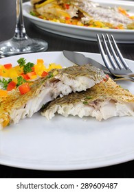 Slices of baked fish dorado with multi-colored pepper diced