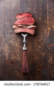 Slices Of Beef Steak On Meat Fork On Wooden Background