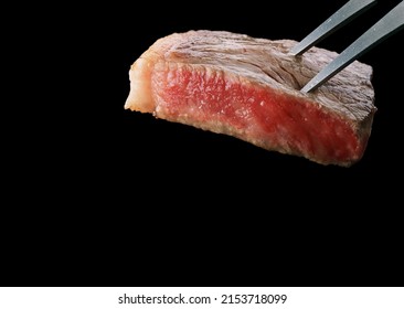 Slices Of Beef Steak On Meat Fork, Isolated On Black Background