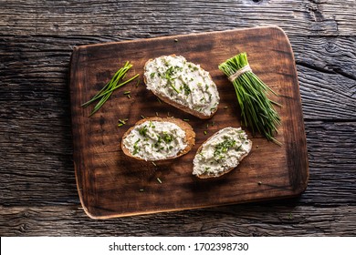 Slices Of Bread With A Cottage Cheese Spread, Freshly Cut Chives, And A Bunch Of Chive Aside Placed On A Dark Brown Cutting Board And Vintage Background.