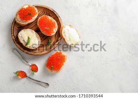 Slices of bread with red caviar on wooden plate on white background. Top view. Copy space.
