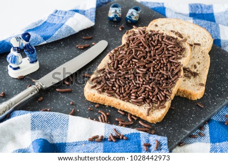 slices of brown bread, wheat, whole grain with typical Dutch hagelslag, chocolate hail. Silver knife, Dutch Delfts blue souvenir, wooden shoe