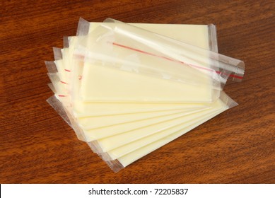Slices Of Cheese Individually Wrapped, Isolated On Table