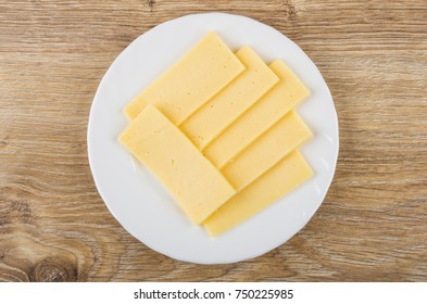 Slices Of Cheese In White Plate On Wooden Table. Top View