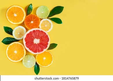 Slices of citruses are laid out in composition in left side of background. Pieces of tangerines, oranges, grapefruits, lemons, limes are lying on yellow canvas. Summer exotic tropical fruits. - Powered by Shutterstock