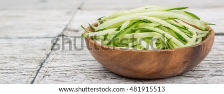 Slices of cucumbers in wooden bowl over white background