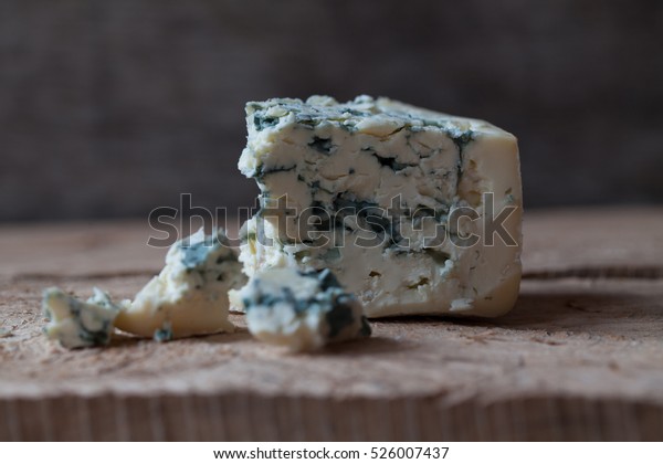 Slices of Danish Blue cheese on an old wooden\
table, selective focus