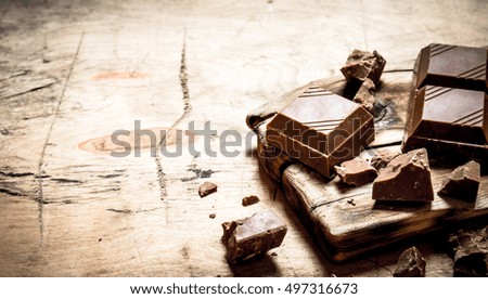 Slices of dark chocolate on the Board. On wooden background.