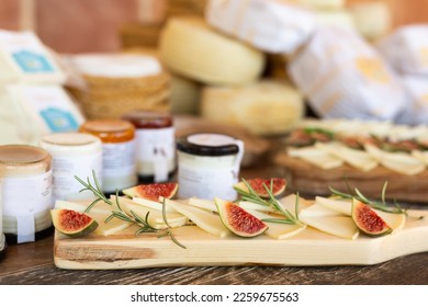 Slices of delicious hard goat cheese offered for tasting, served on cutting boards with sweet ripe figs garnished with fragrant fresh herbs on wooden table in artisan cheese factory.. - Powered by Shutterstock