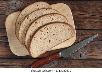 Slices of fresh bread on cutting board on wooden table, top view