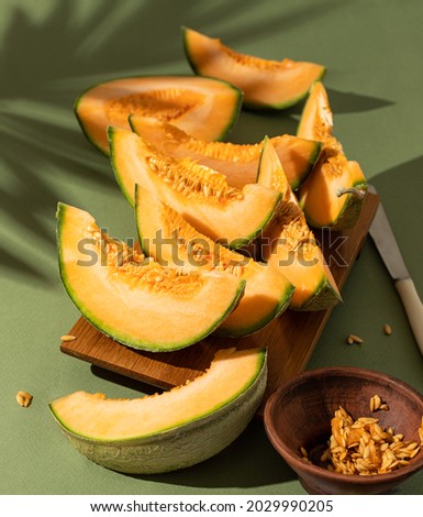 Slices of fresh delicious Cantaloupe melon on a wooden stand on a green background