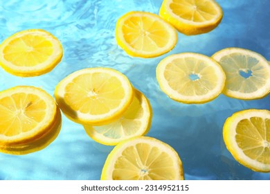 Slices of fresh lemon in water on blue background - Shutterstock ID 2314952115