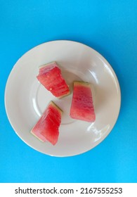 Slices Of Fresh Watermelon On A White Small Plate Isolated On A Light Blue Background