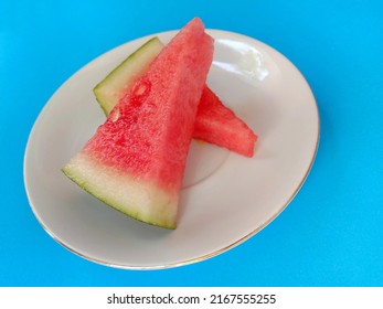 Slices Of Fresh Watermelon On A White Small Plate Isolated On A Light Blue Background