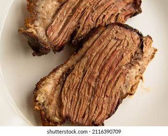 Slices of freshly grilled beef brisket on a white plate