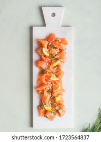 Slices of homemade smoked salmon fillet with dill and lemon served on marble cutting board on light background. Top view. Healthy food