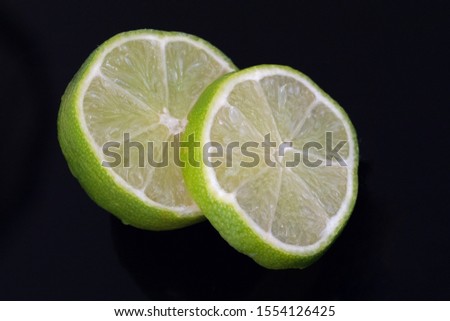 Slices of juicy green lime on a black surface
