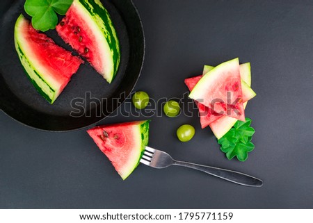 Slices of juicy ripe red watermelon pinned on a fork on a black background