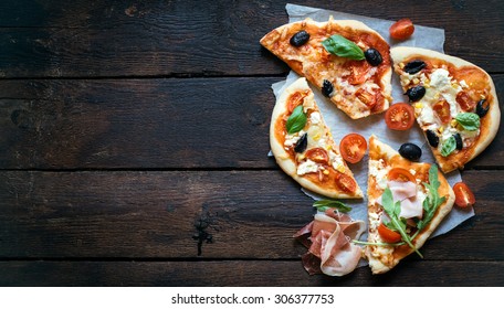 Slices of mini pizza variety served on wooden board and background,from above and blank space