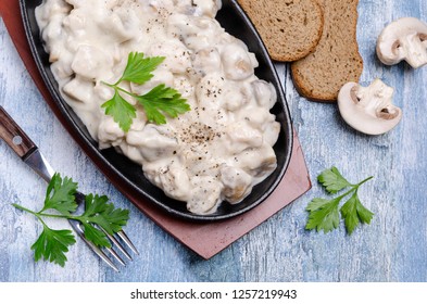 Slices of mushrooms and meat with white sauce on wooden background. Selective focus.