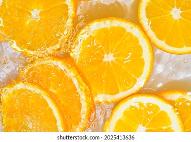 Slices of oranges in water on white background. Oranges close-up in liquid with bubbles. Slices of juicy ripe oranges in water. Macro image of fruits in water