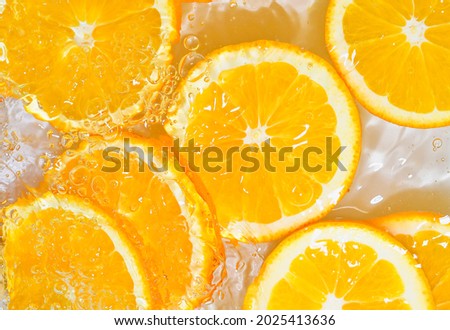 Slices of oranges in water on white background. Oranges close-up in liquid with bubbles. Slices of juicy ripe oranges in water. Macro image of fruits in water. Colour picture of orange slices in water