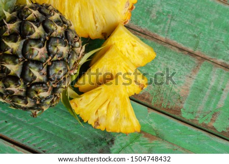 Slices of pineapple on green wood.