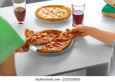 Slices of pipperoni pizza in the hands of children on the white table background. The concept of a snack for children, home made, home party.
