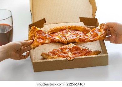 Slices of pipperoni pizza in the hands of children on the background of a cardboard box . The concept of a snack for children to take away, delivery online.