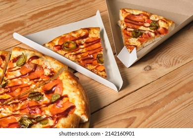 a slices of pizza in a cardboard box in the shape of a triangle for serving and take away