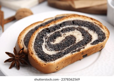 Slices of poppy seed roll and anise star on plate, closeup. Tasty cake
