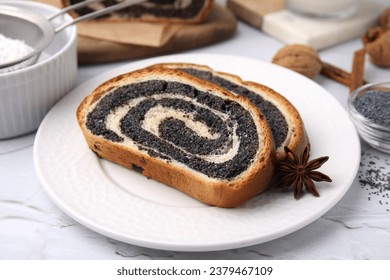 Slices of poppy seed roll and anise star on white textured table, closeup. Tasty cake