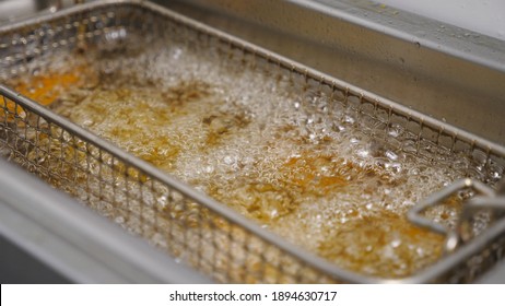 Slices Of Potatoes Rustic Is Frying In Hot Boiling Oil At Cuisine. Crispy French Fries Is Cooking Into Deep Fryer. Process Of Making Fast Food At Kitchen. Concept Of Preparing Food. Close Up Slow Mo