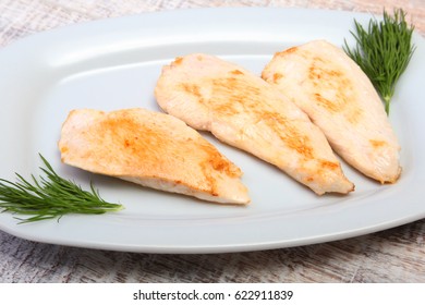 Slices of roasted chicken breast and tomato on white plate