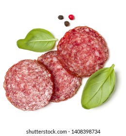 Slices of salami isolated on white background closeup. Sausage and basil leaves top view.