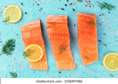 Slices Of Salmon With Lemon And Dill, Overhead Shot With Salt And Pepper On A Blue Background. Cooking Fish, A Flat Lay Composition