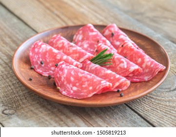 Slices of spanish salami with fresh rosemary and peppercorn on the plate