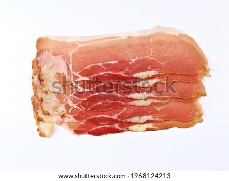 Slices of Speck, smoked pork belly on white background. It is originally from the Tyrol and german tradition and then spread with many variants throughout Europe.