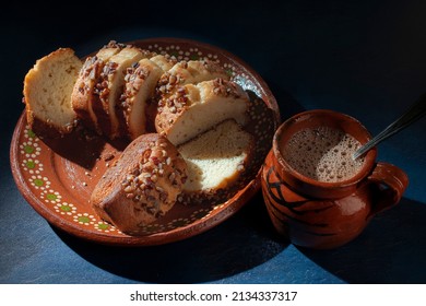 Slices Of Sweet Bread With Pieces Of Walnuts On Top, Over A Mud Or Clay Mexican Plate And A Blue Surface Table, A Clay Cup Of Chocolate. Overhead, Top View Flat Lay Horizontal Macro Photography.